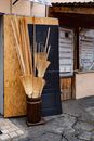 Pile of traditional straw broom sticks for sale placed in wooden bin on old town street