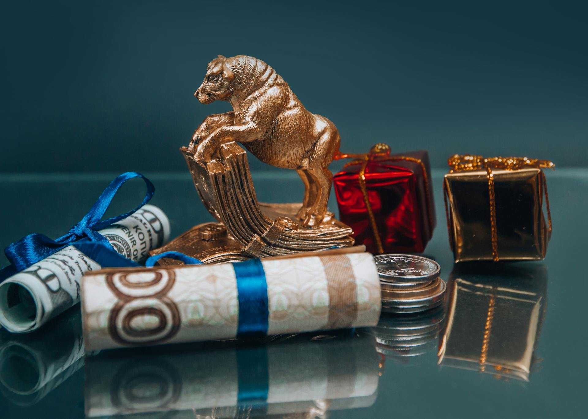 Golden ox figurine with small wrapped New Year presents composed with coins stack and rolled various banknotes