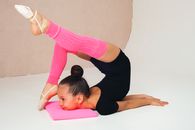 Side view full body of flexible girl doing yoga exercise on floor in studio