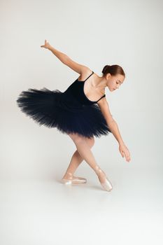 Graceful ballerina in a classic tutu performing a pose in a studio setting.
