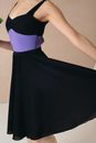 Crop anonymous slim female in black and violet wear touching bottom of dress while dancing in studio