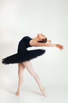 A graceful ballerina in a black tutu executes a perfect dance pose against a white background.
