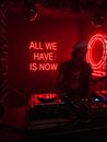 DJ performing music near signboard all we have is now