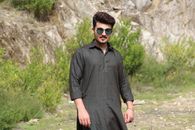Man in Black Dress Shirt and Black Pants Standing Near Green Grass