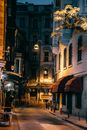 Narrow street with old buildings and shining lamps
