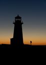 Unrecognizable backpacker silhouette against lighthouse at dusk