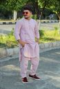 Man in Pink Dress Shirt and Pink Pants Standing on Gray Asphalt Road