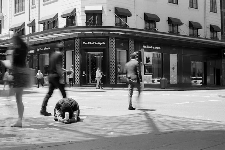 People Passing A Man Begging For Money On A City Street 