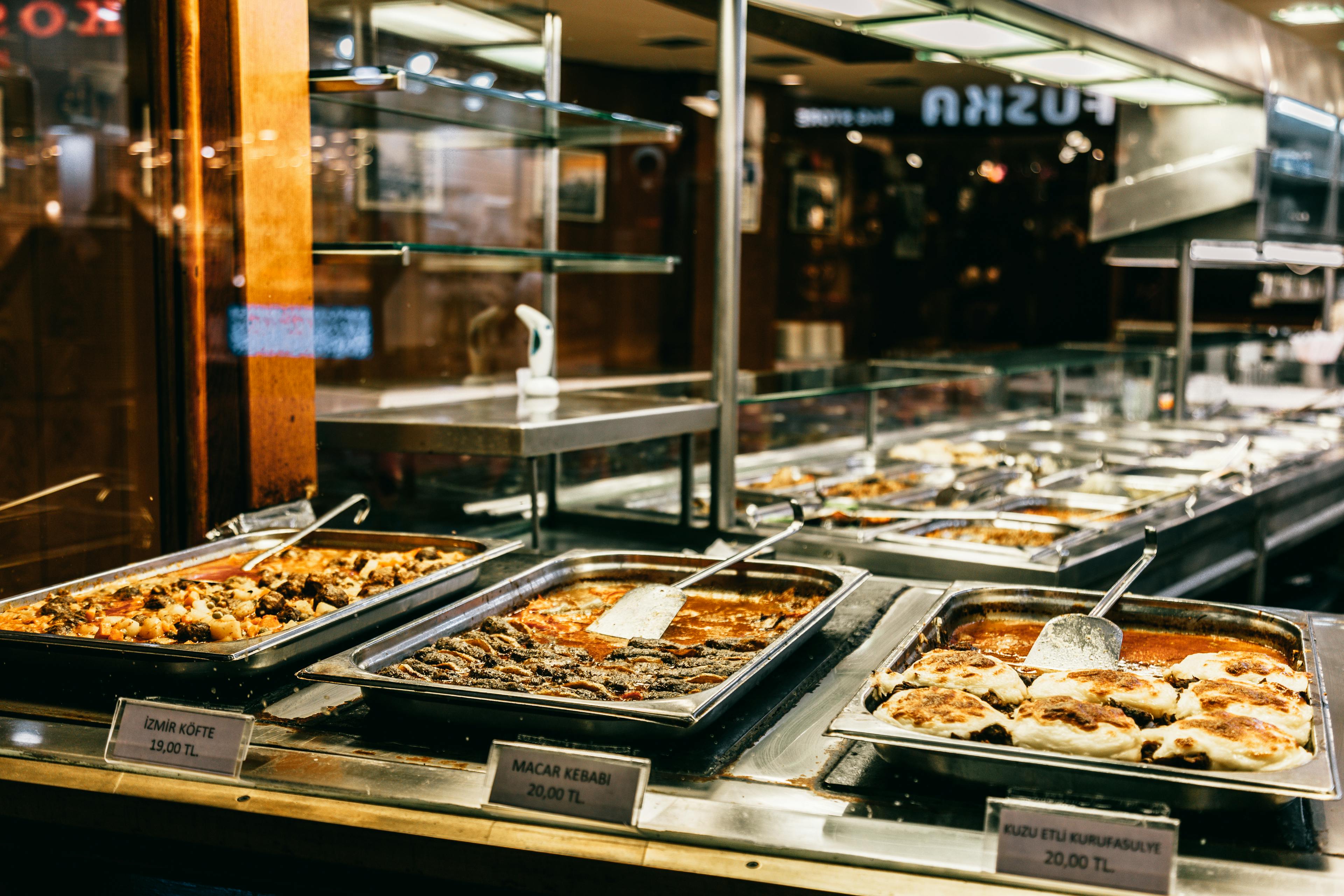 Different hot dishes in big bowls selling in self service restaurant at night