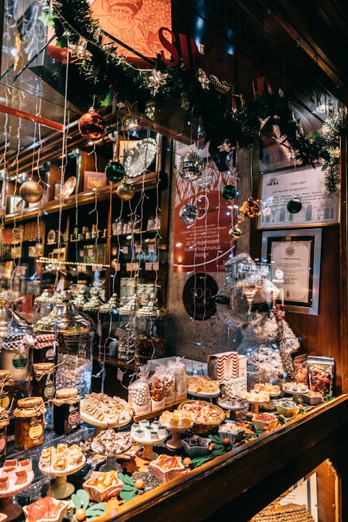 Showcase of assorted traditional sweets in candy shop decorated with string lights and balls for Christmas