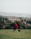 Person Sitting on Red Folding Chair on Green Grass Field