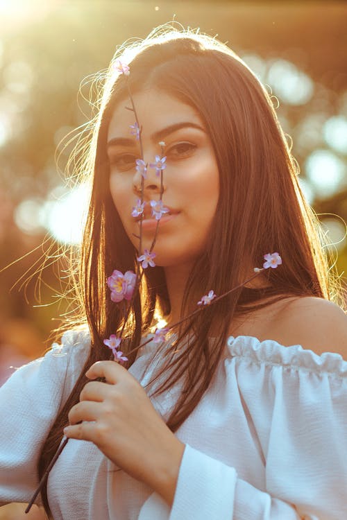 Woman in White Off Shoulder Top Holding Flowers