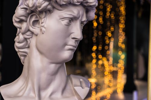 Free Elegant marble bust with a blurred vibrant light bokeh background, creates a classic and artistic scene. Stock Photo