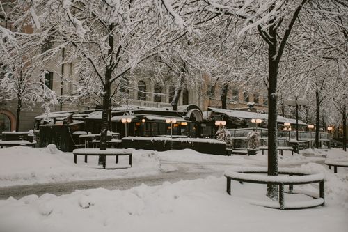 Free A serene winter cityscape featuring a snow-covered cafe and street in a quiet urban setting. Stock Photo