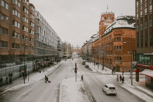A bustling winter street in a snowy urban cityscape, highlighting architectural diversity.