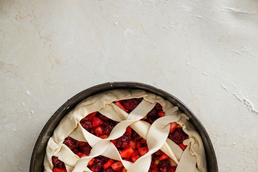 Overhead view of an unbaked cherry pie with a lattice crust on a floured surface.