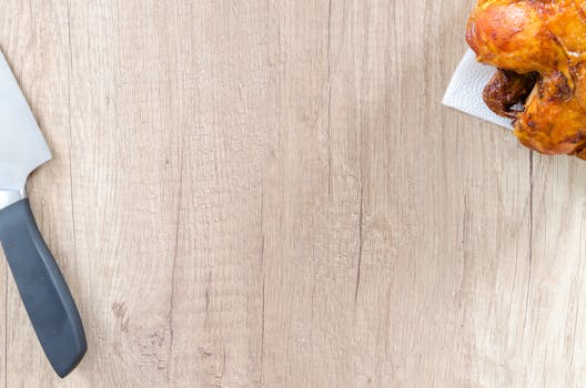 Crispy roast chicken with chef's knife on a rustic wood board. Perfect for food blogs.