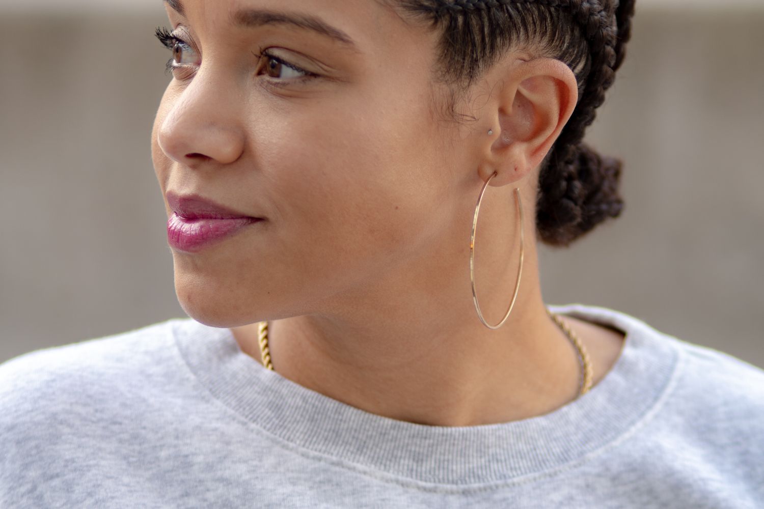 Woman in a grey sweatsuit with gold hoop earrings