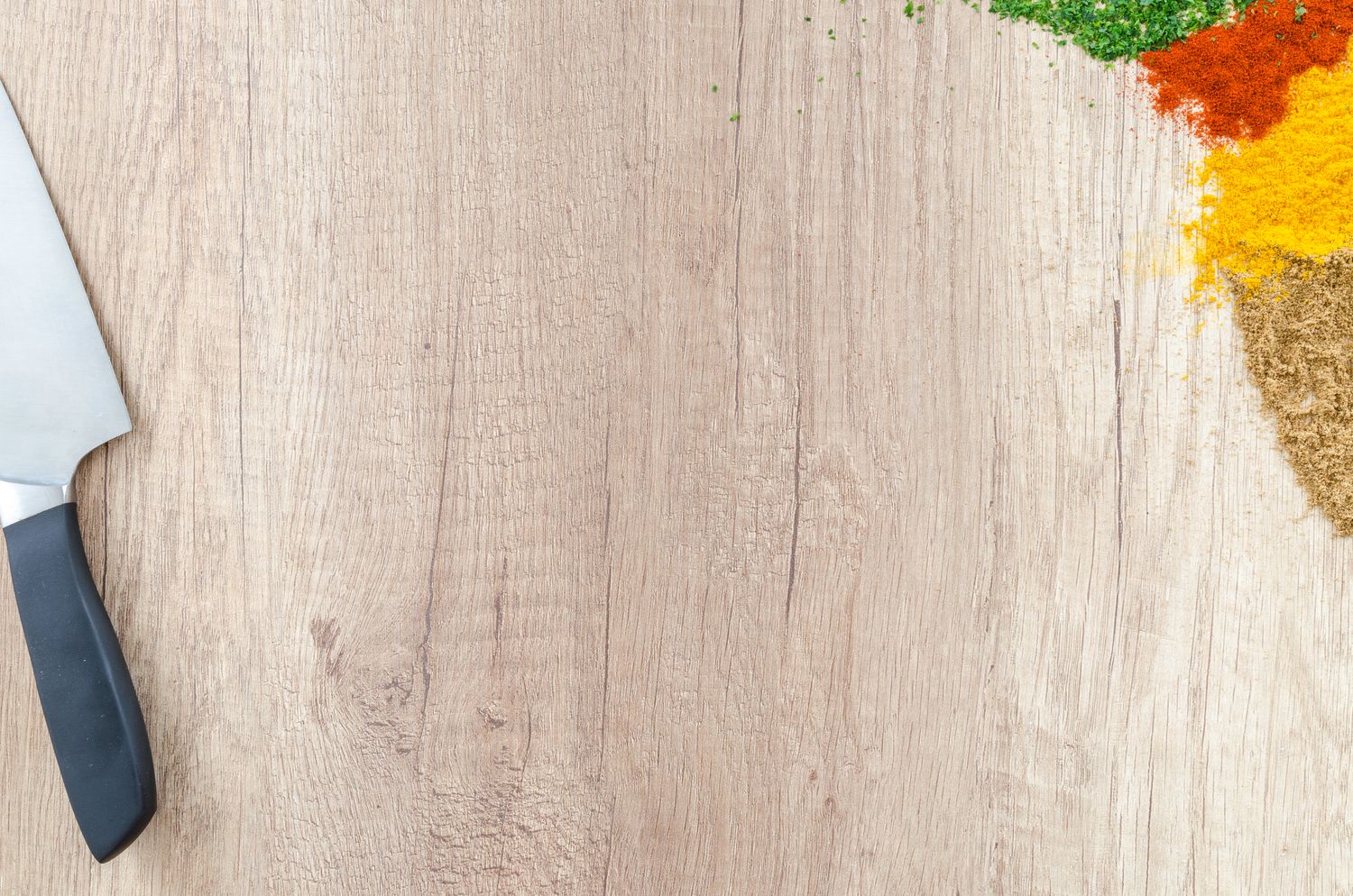 Chef knife and seasonings arranged on a light wooden preparation surface