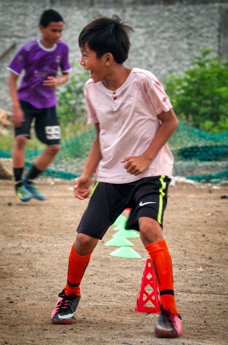 Ethnic Boy Playing Football On Street