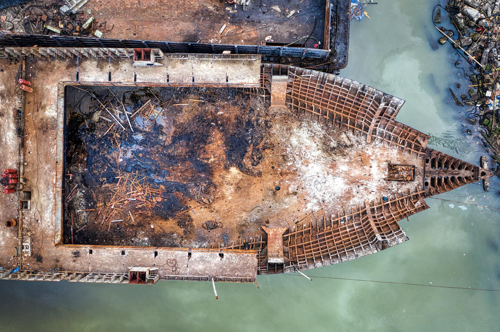 Drone view of old rusty ship floating in polluted water and moored in abandoned dirty port in daylight