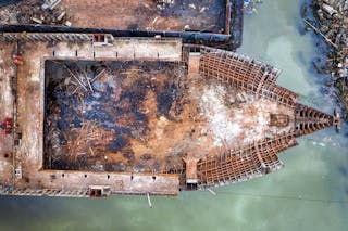 Drone view of old rusty ship floating in polluted water and moored in abandoned dirty port in daylight