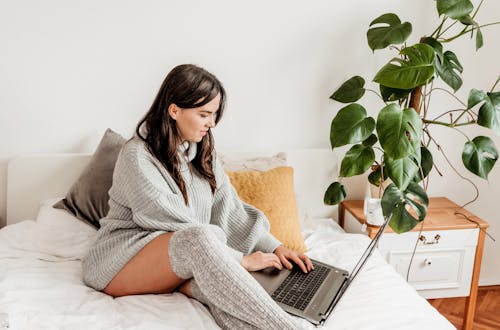 Interested woman typing on laptop in bedroom