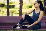 一位年轻女子优雅地坐在公园的长凳上，展现出宁静与时尚