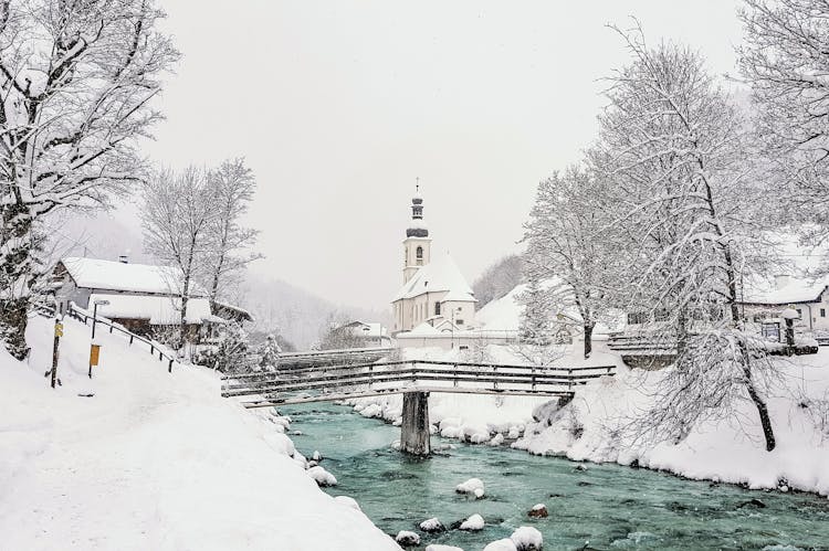 Old Bridge Over River Against Church In Winter City