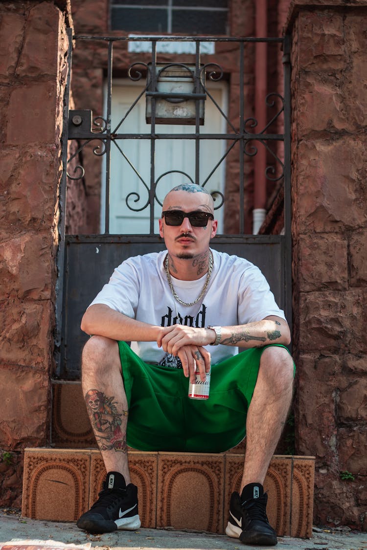 Young Man With Tattoos Sitting On Stairs Outside