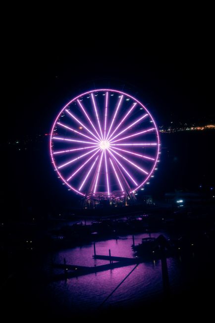 Brightly lit ferris wheel glowing in the dark night sky at an amusement park in Fort Washington.