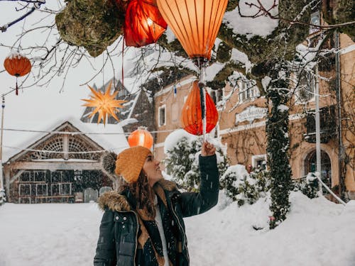 Smiling traveler touching decorative lanterns in winter city