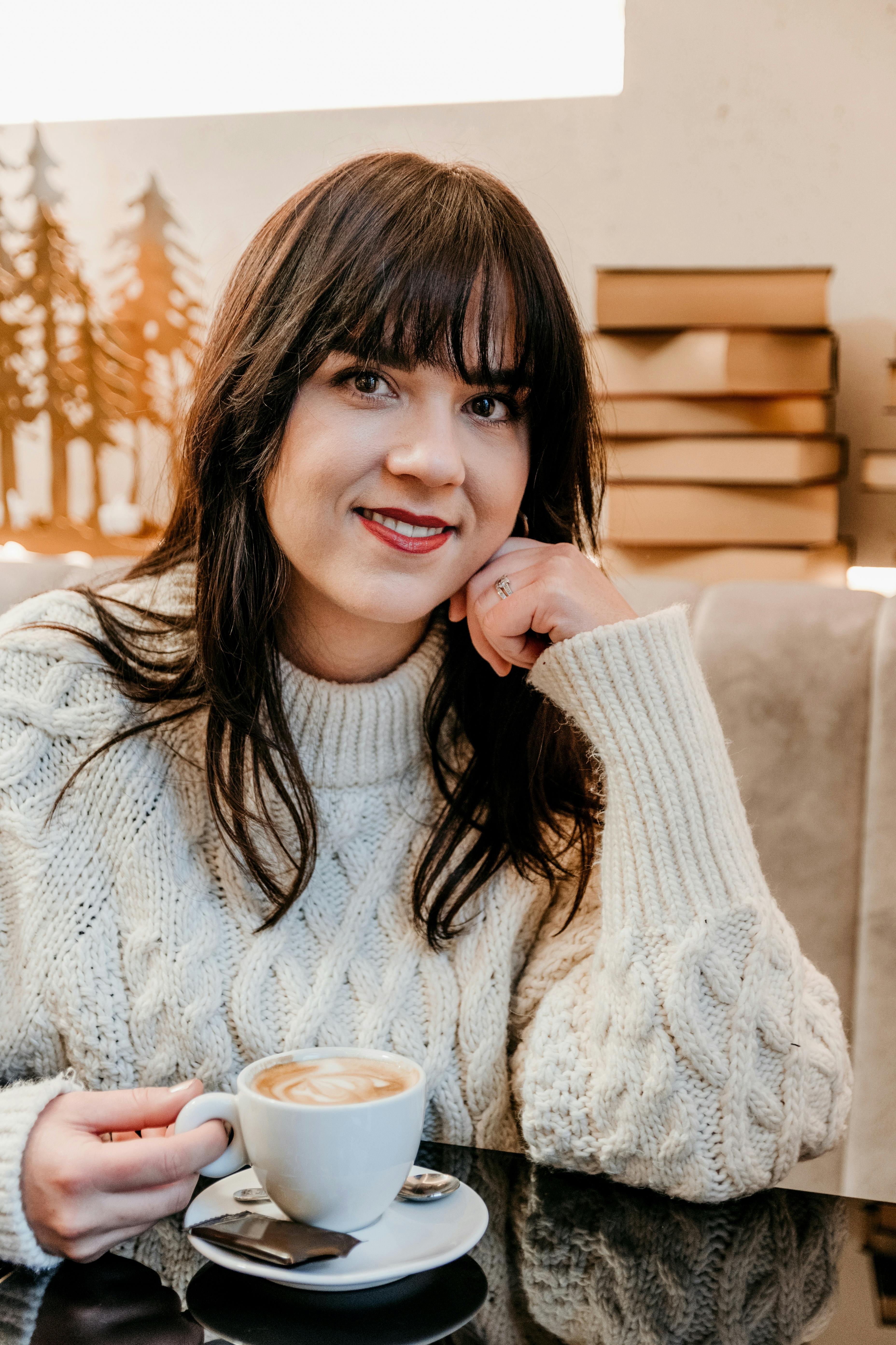 cheerful woman with up of aromatic cappuccino sitting in cafeteria