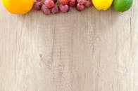 木制砧板上排列着新鲜的橙子、葡萄、柠檬和酸橙，色彩鲜艳