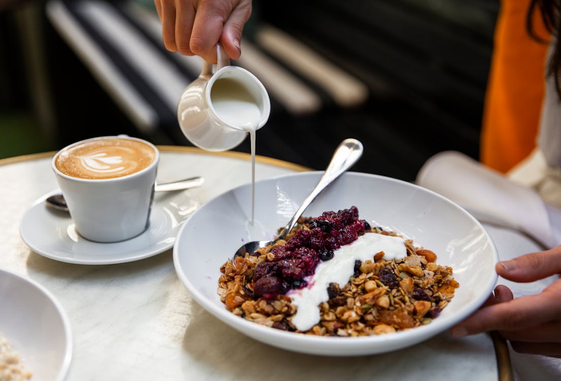 Unrecognizable person having breakfast at table with coffee and muesli