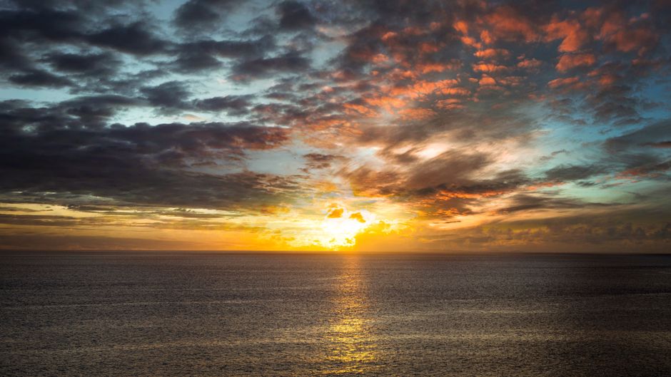 Breathtaking sunset over the ocean with dramatic clouds and vivid golden colors