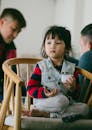 Little Girl Sitting on Brown Wooden Chair