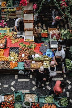 A bustling scene of people shopping at a vibrant farmers market in Funchal, Madeira.