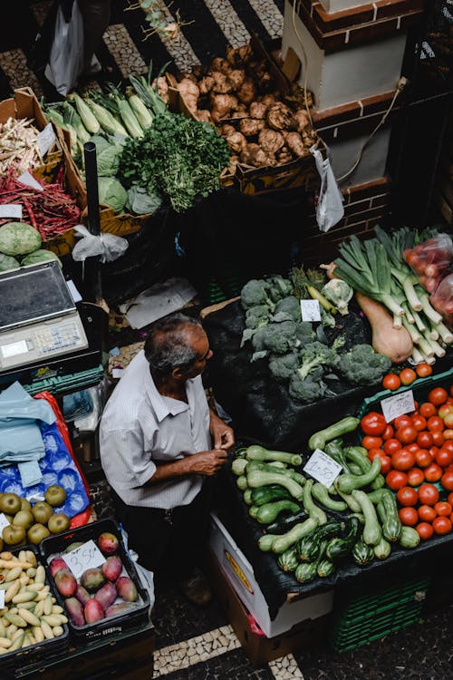 High-Angle Shot of a Man Looking at Vegetables on a Market