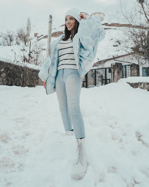 Stylish smiling woman on snow in countryside