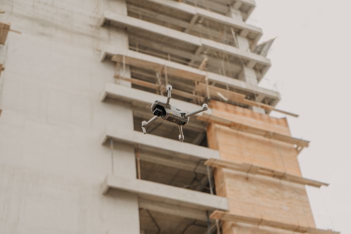 A small aircraft hovering beside a building — Shalom de León on Pexels
