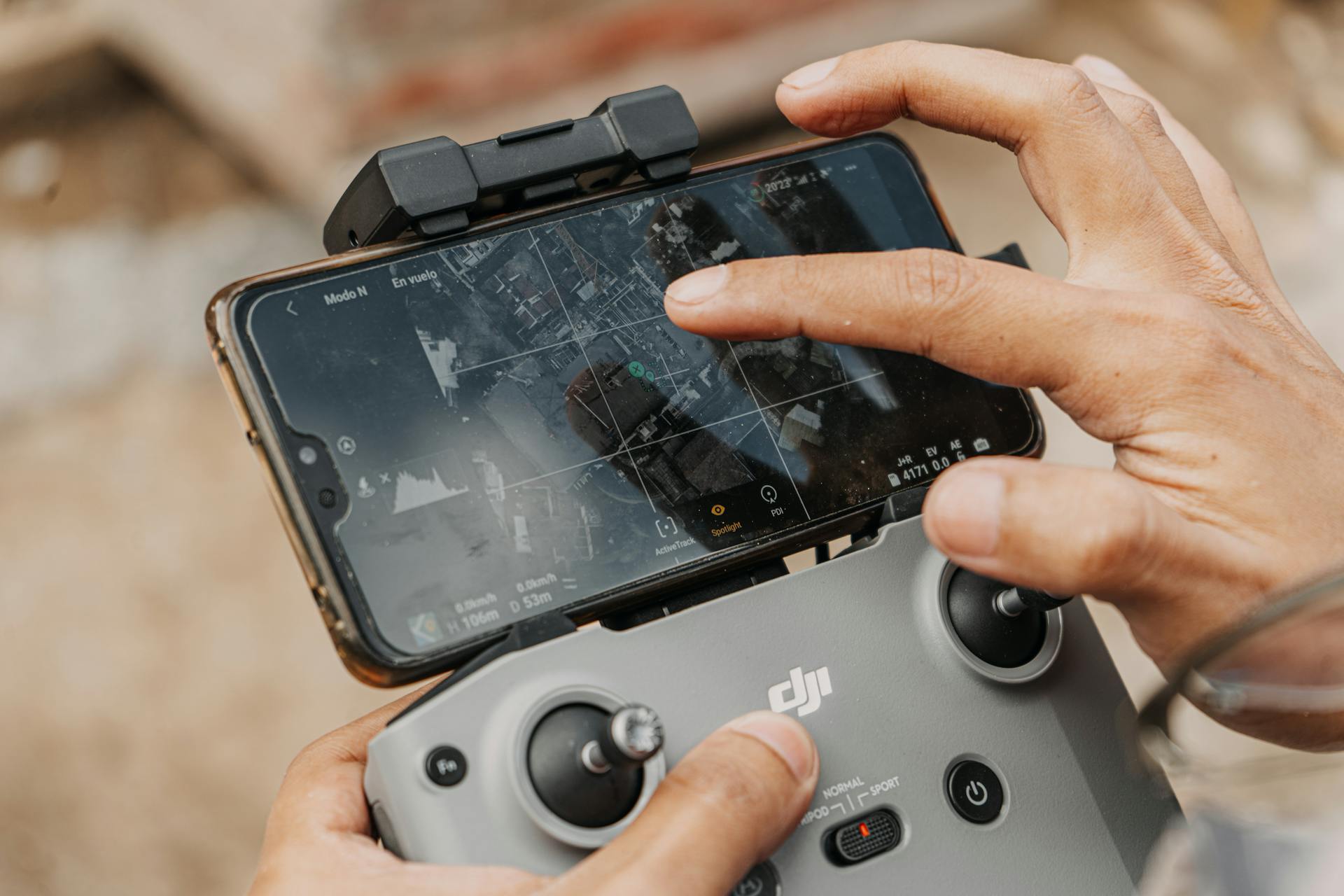 Hands manipulating DJI drone controller with smartphone, showcasing navigation technology.