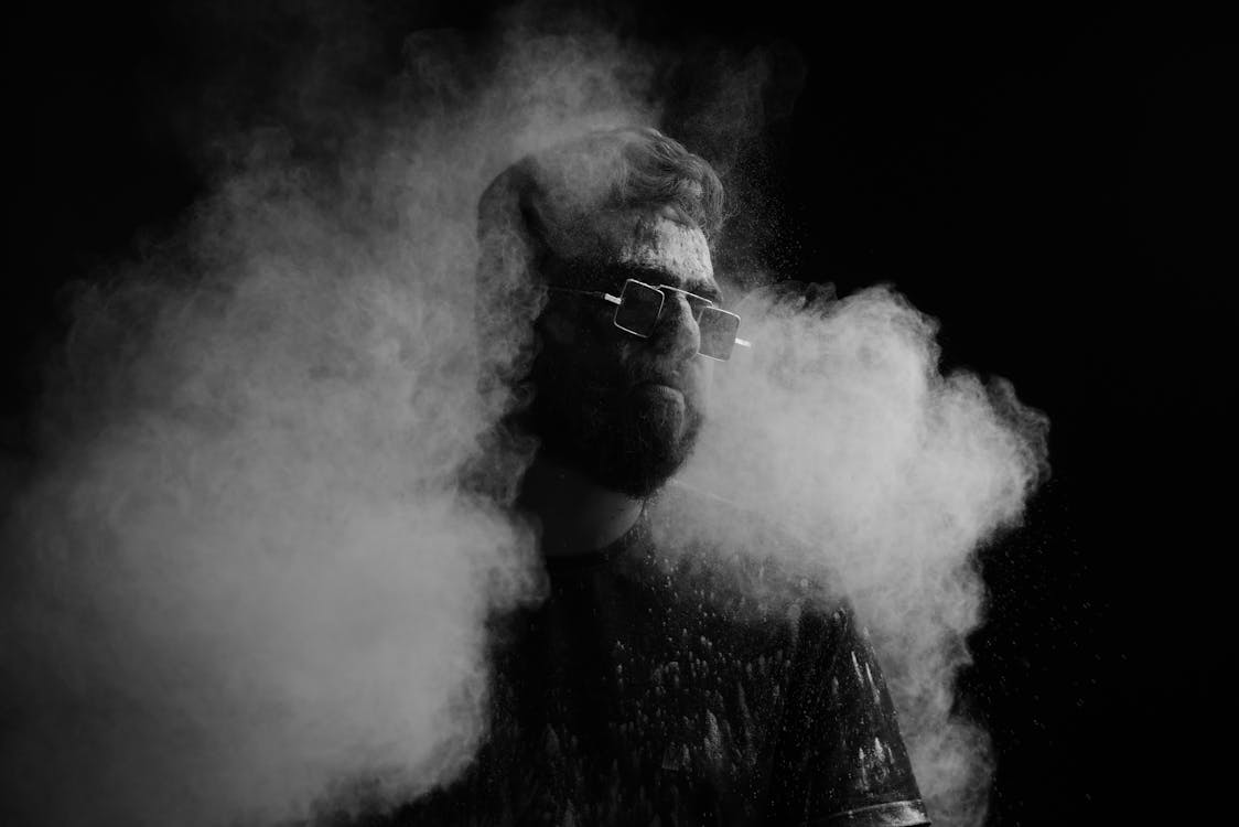 Black-and-White Photo of a Bearded Man with Sunglasses Surrounded by Smoke