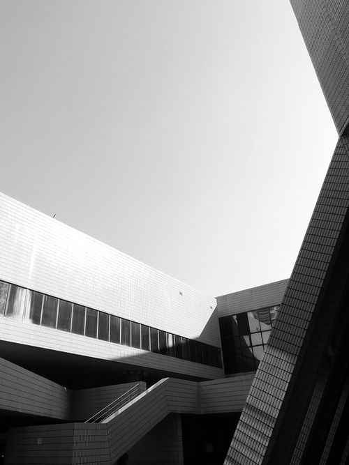 Free Black and white of contemporary building exterior with large glass windows and geometric design in sunlight Stock Photo