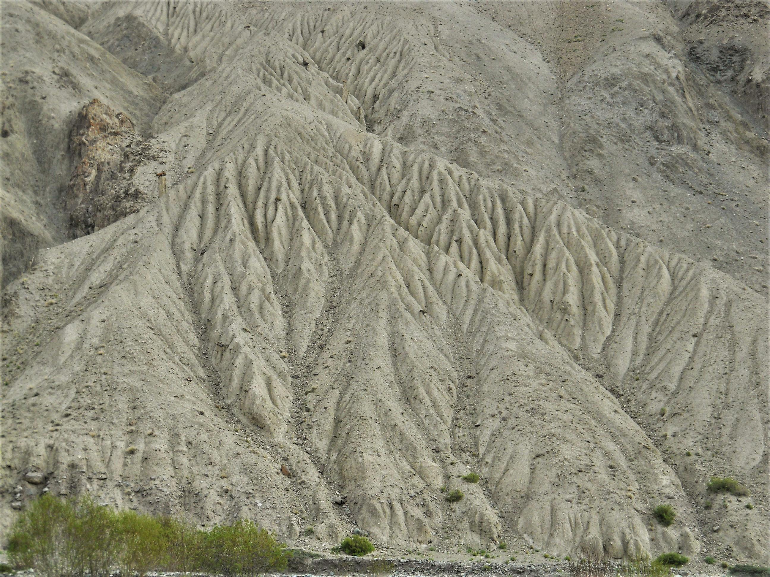 Dramatic erosion patterns on rocky terrain in Ladakh, India showing natural sculpting by wind and water.