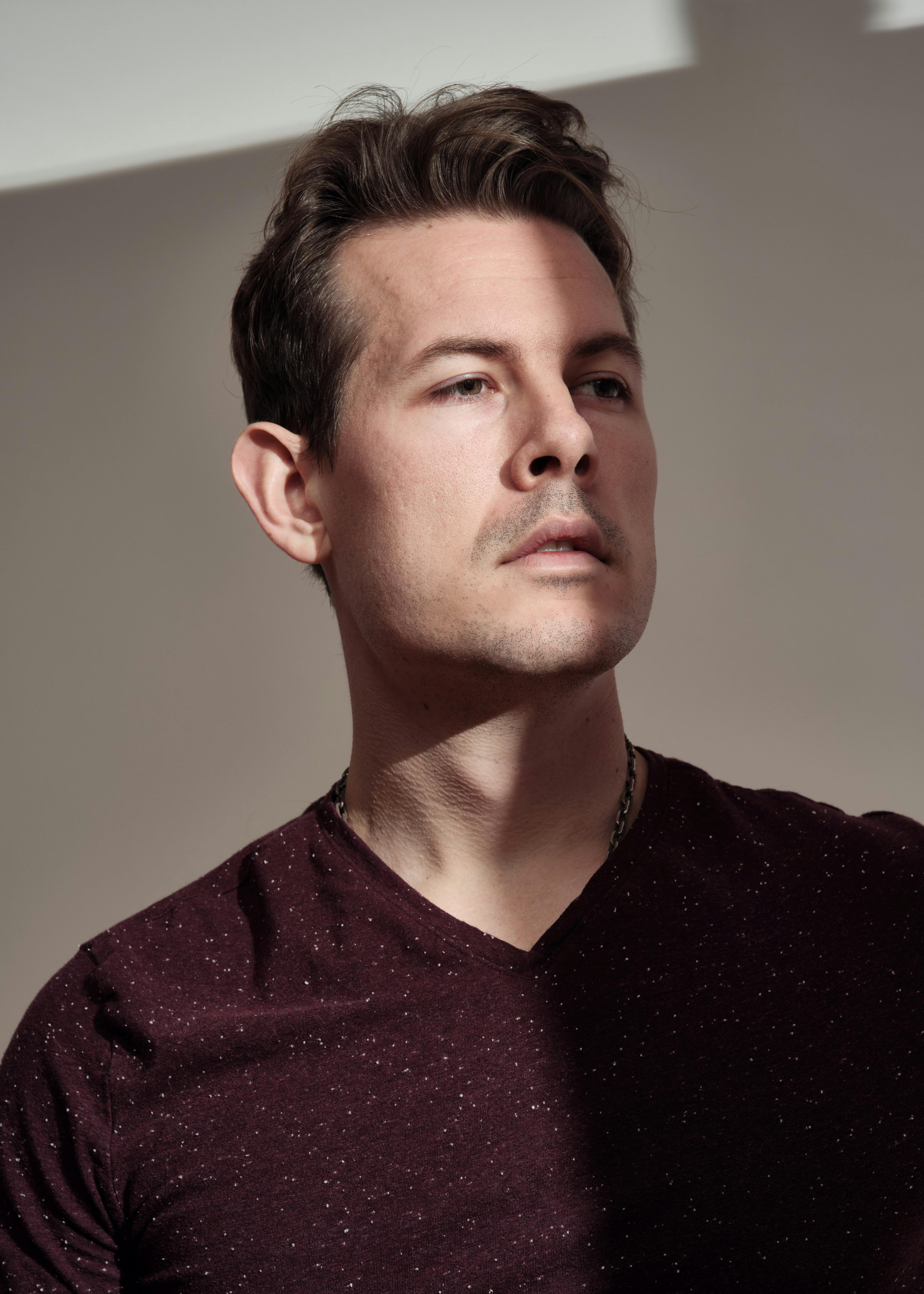 Close-up headshot of a man in soft lighting, conveying reflection and depth.