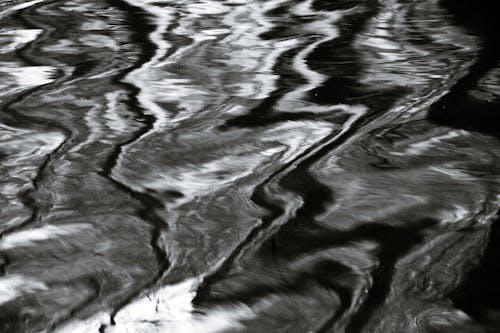 From above black and white of textured backdrop of river with fast water fluids