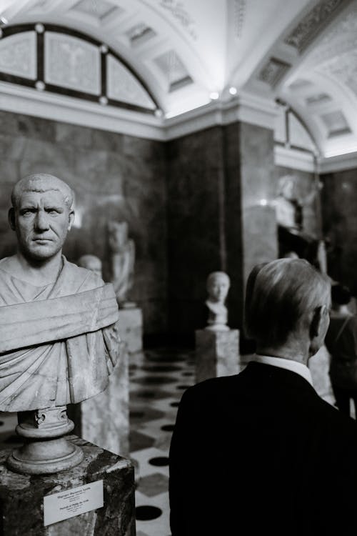 Unrecognizable man against bust of Roman emperor in museum