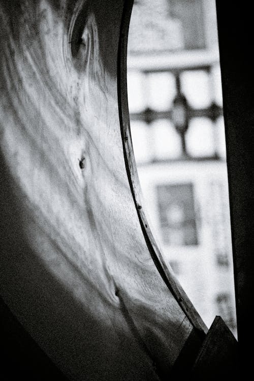 Black and white of wavy curtain against window and aged urban house exterior in daytime