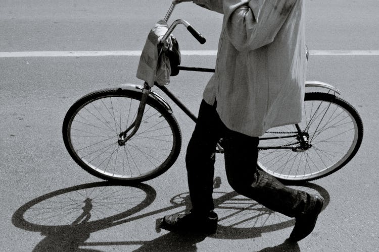 Unrecognizable Person Walking On Street With Bike